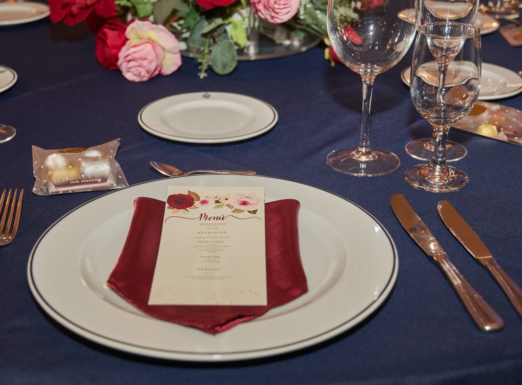 Puesto de mesa con servilleta roja sobre mantel azul noche
